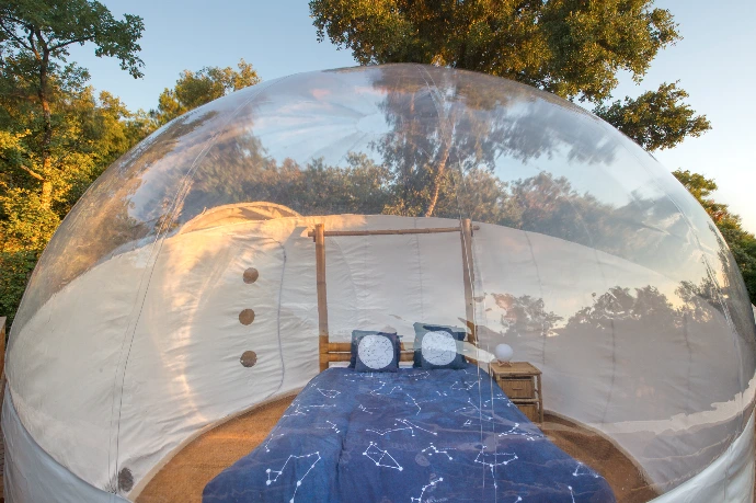 Intérieur cosy de la bulle Orion avec grand lit confort face aux étoiles.